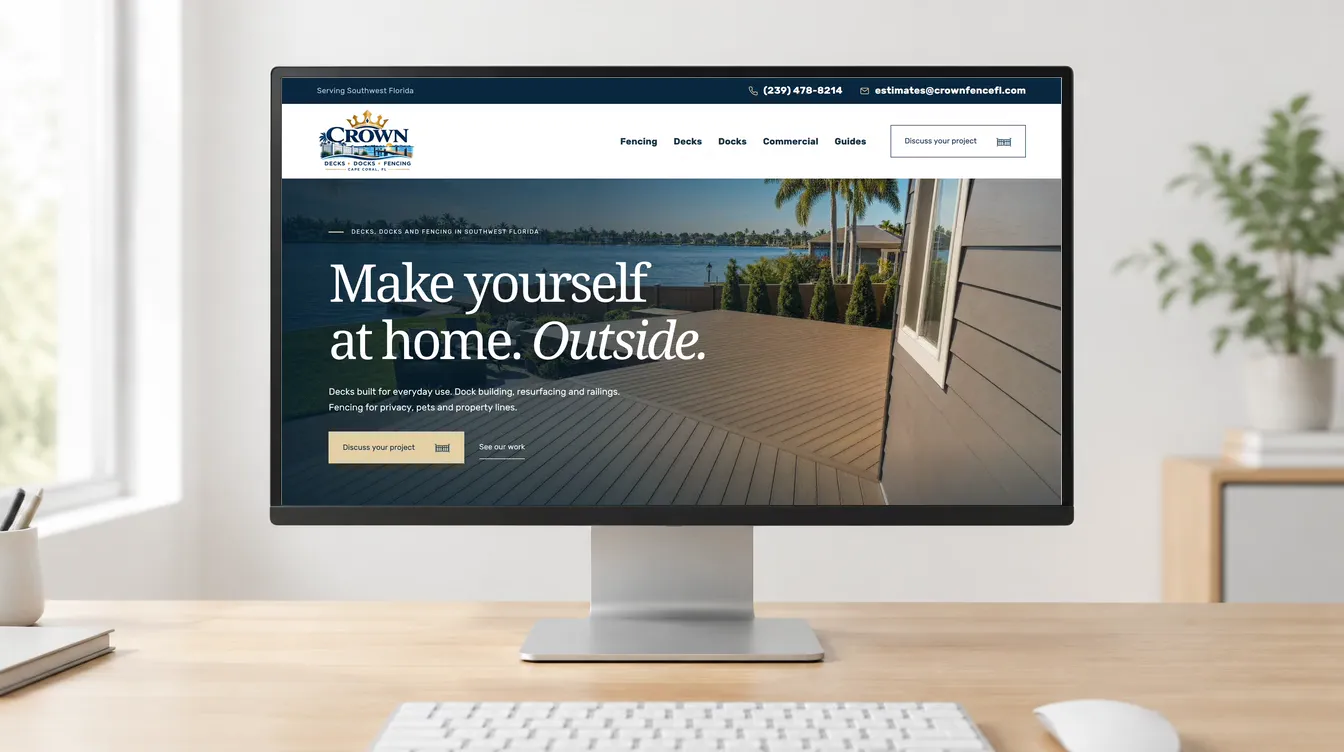 The Crown Fence Co. homepage on a desktop monitor on a wooden desk, with keyboard and mouse